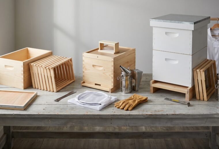 Three beekeeping starter kits compared by budget tier, entry, complete, and deluxe, on a workbench